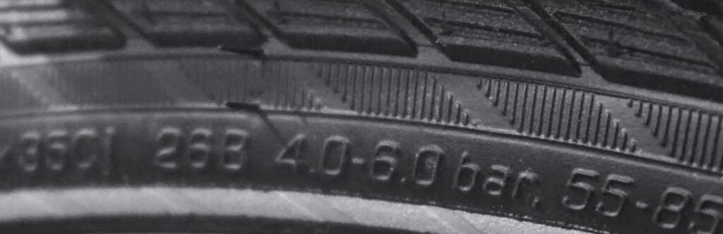 Nahaufnahme eines Fahrradreifens mit Angaben zu Druck und Breite, passend für Rennrad, Trekkingbike, E-Bike, MTB.