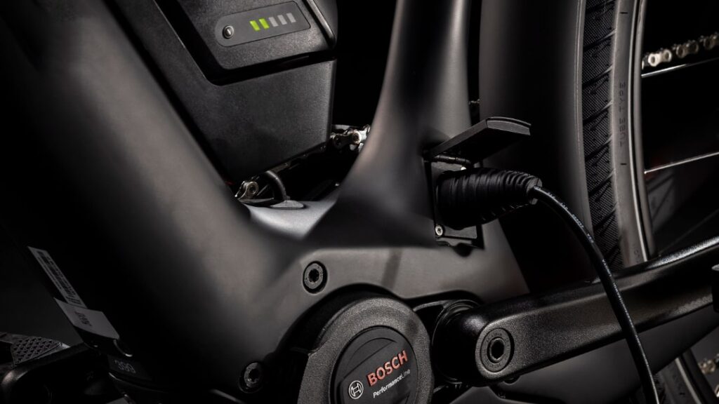Bosch eBike-Akku wird geladen, Nahaufnahme des Ladeanschlusses und Akkustandsanzeige am Fahrradrahmen.