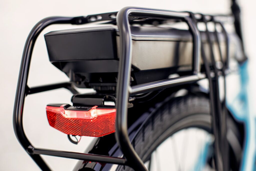 Bosch eBike-Akku auf Gepäckträger, Nahaufnahme, mit Rücklicht und Fahrradrahmen im Hintergrund.