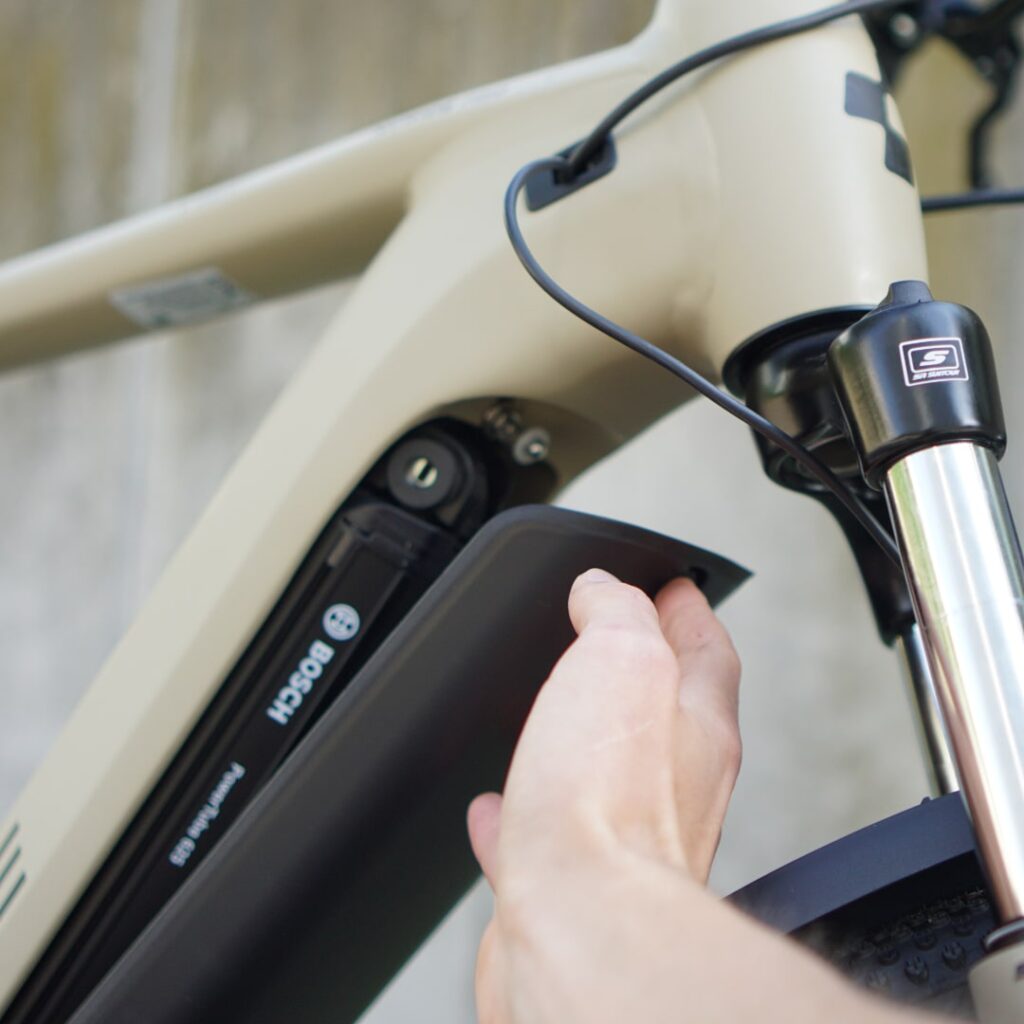 Cube Nuride Hybrid Pro 625 2022: Powertube-Abdeckung wird geöffnet, um den Bosch-Akku freizulegen.