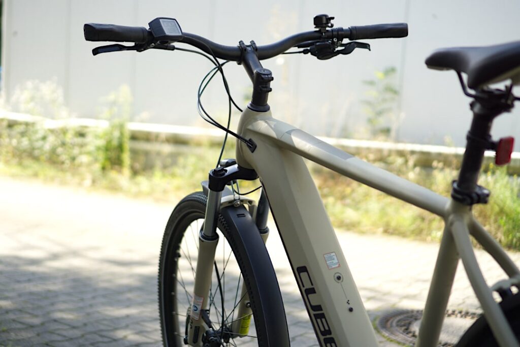 Cube Nuride Hybrid Pro 625 2022: Detailansicht des Rahmens und Lenkers im Freien.