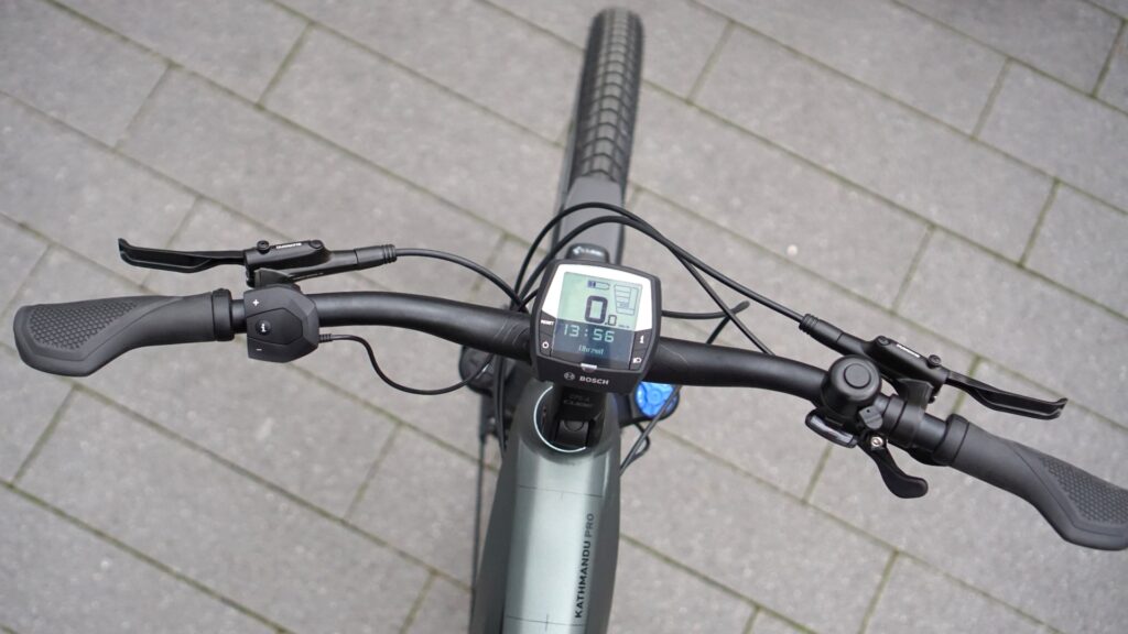 Cube Kathmandu Hybrid PRO 625 2022 Cockpit mit Bosch Intuvia Display und ergonomischen Griffen auf grauem Pflaster.