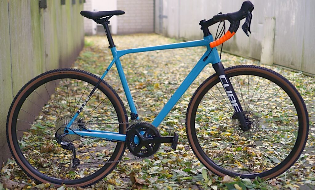 Cube Cross Race Pro 2022, blaues Cyclocross-Rad auf herbstlichem Weg, Seitenansicht, ideal für Gelände und Straße.