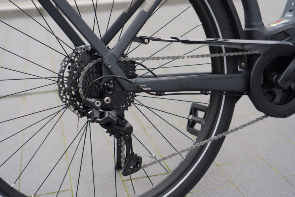 Cube Kathmandu Hybrid 625 2022: Detailansicht der Fahrradkette und des Antriebs auf grauem Boden.