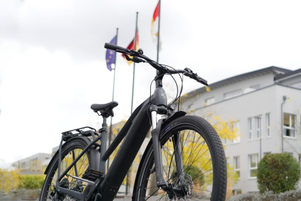 Cube Kathmandu Hybrid 625 E-Bike vor Fahnen und Gebäuden, Fokus auf Design und Ausstattung.