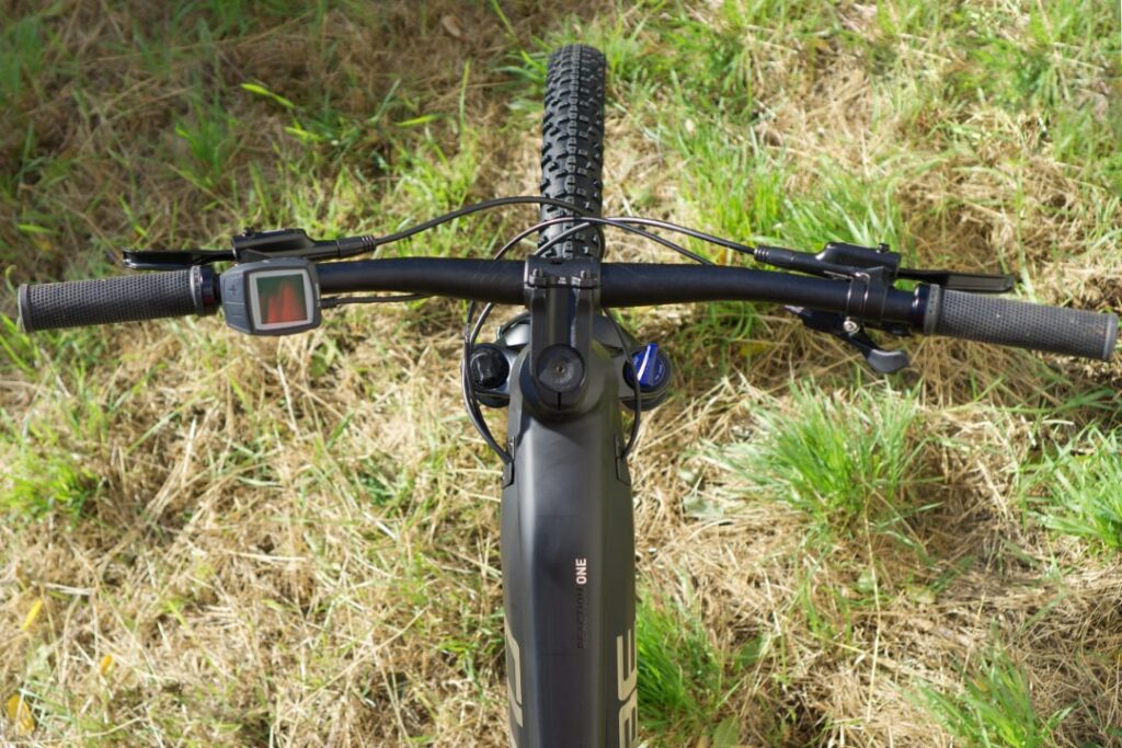 Cube Reaction Hybrid ONE 625 Cockpit mit Display und Lenker auf Grasfläche von oben.