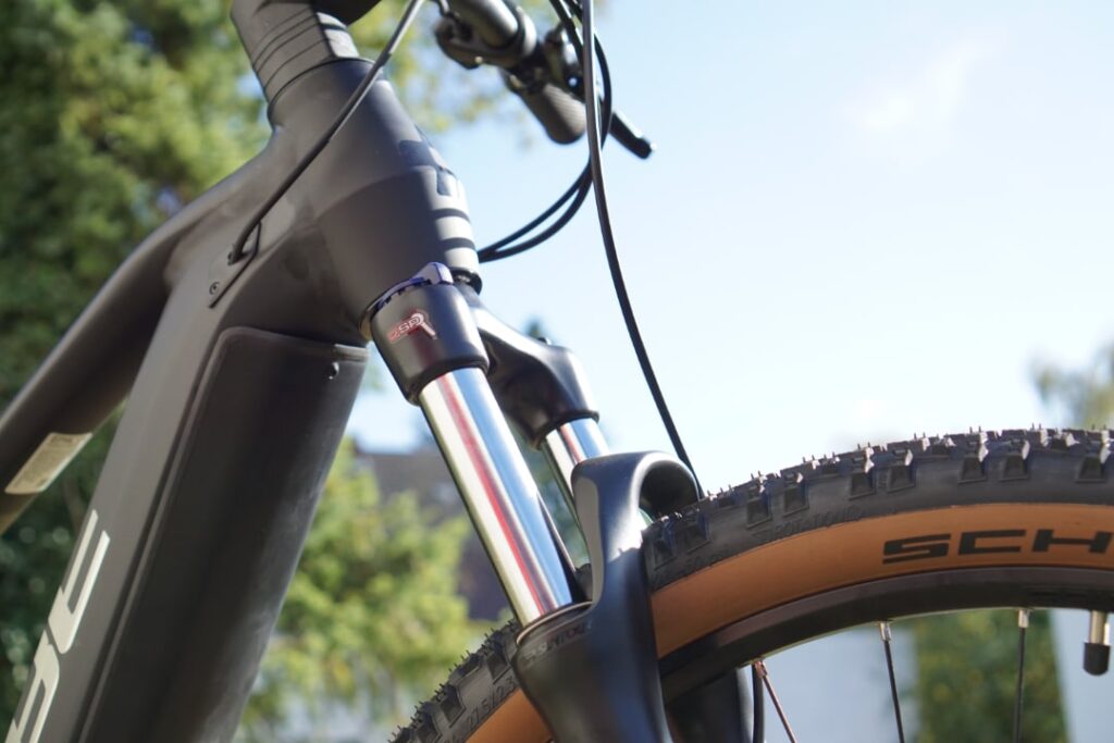 Detailaufnahme eines Cube Reaction Hybrid ONE 625 E-Bikes mit Smart Sam Reifen und Federgabel im Freien.