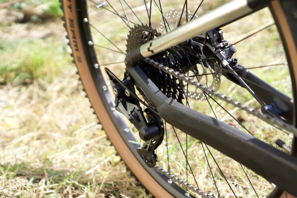 Cube Reaction Hybrid ONE 625 Hinterrad mit Shimano Deore Schaltwerk im Detail auf grasbewachsenem Untergrund.