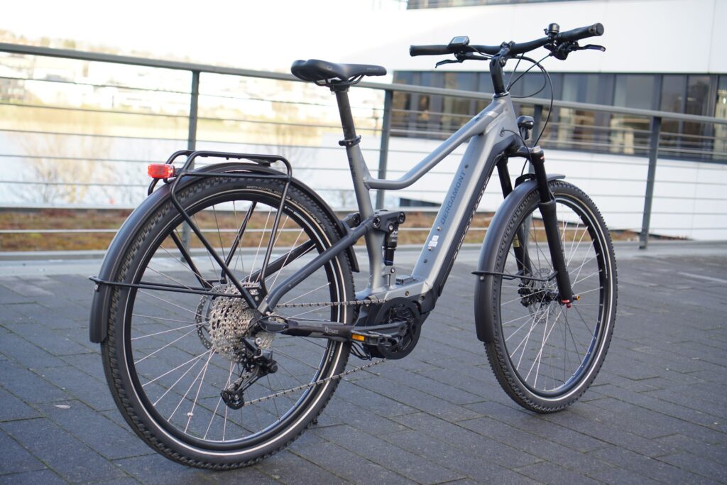 Bergamont E-Horizon FS Expert 2022 mit Gepäckträger, aufgenommen auf einem modernen Stadtbalkon.