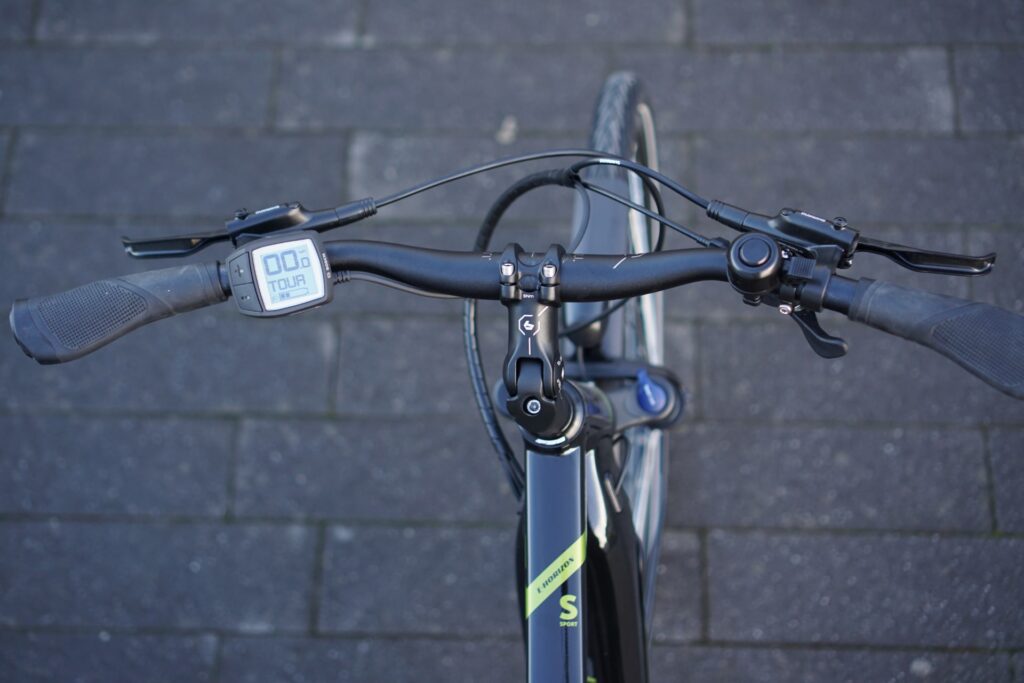 Cockpit-Ansicht des Bergamont E-Horizon Sport 2022 mit Display und Lenker auf grauem Pflaster.