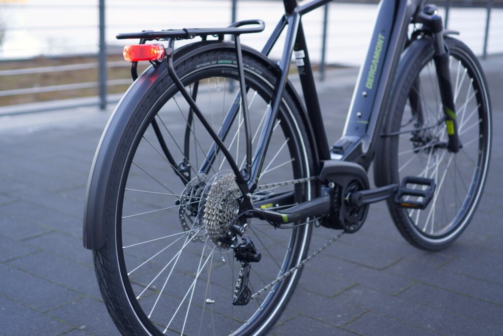 Bergamont E-Horizon Sport 2022 mit Gepäckträger, Shimano-Schaltung und robustem Rahmen auf gepflastertem Untergrund.