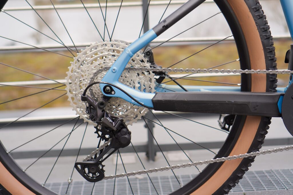 Cube Reaction Hybrid SL 750 2022 mit Deore XT Schaltwerk, Detailansicht des Hinterrads und der Kettenschaltung.