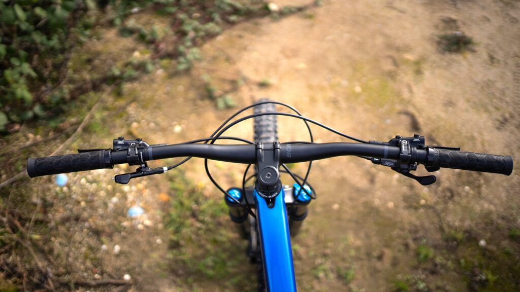 Trek Fuel EX 8 XT 2022 Cockpit mit Lenker und Bremshebeln auf Waldweg von oben fotografiert.