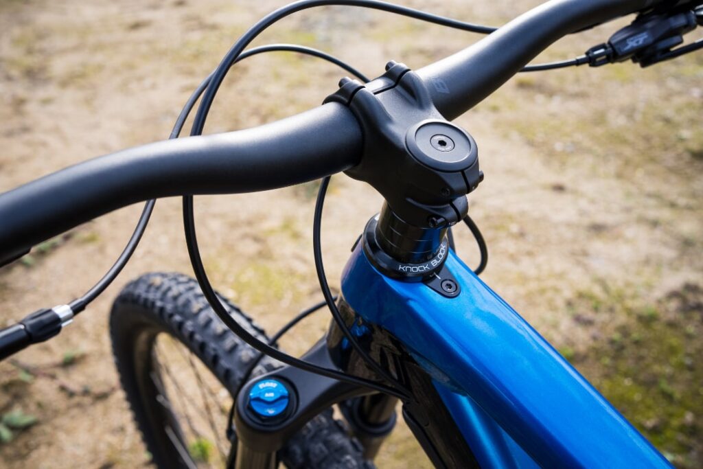Trek Fuel EX 8 XT 2022: Nahaufnahme des blauen Rahmens mit Knock Block-Technologie und Lenkerdetails.