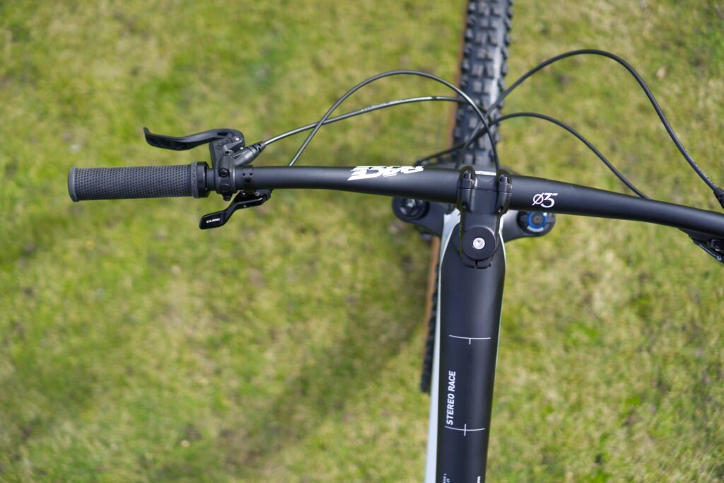 Cube Stereo 150 C:62 Race 2022 Cockpit mit Lenker und Bremshebel, Ansicht von oben auf grünem Hintergrund.