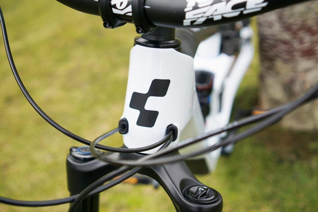 Cube Stereo 150 C:62 Race 2022 Steuerrohr mit Kabeln und Logo auf grünem Hintergrund.