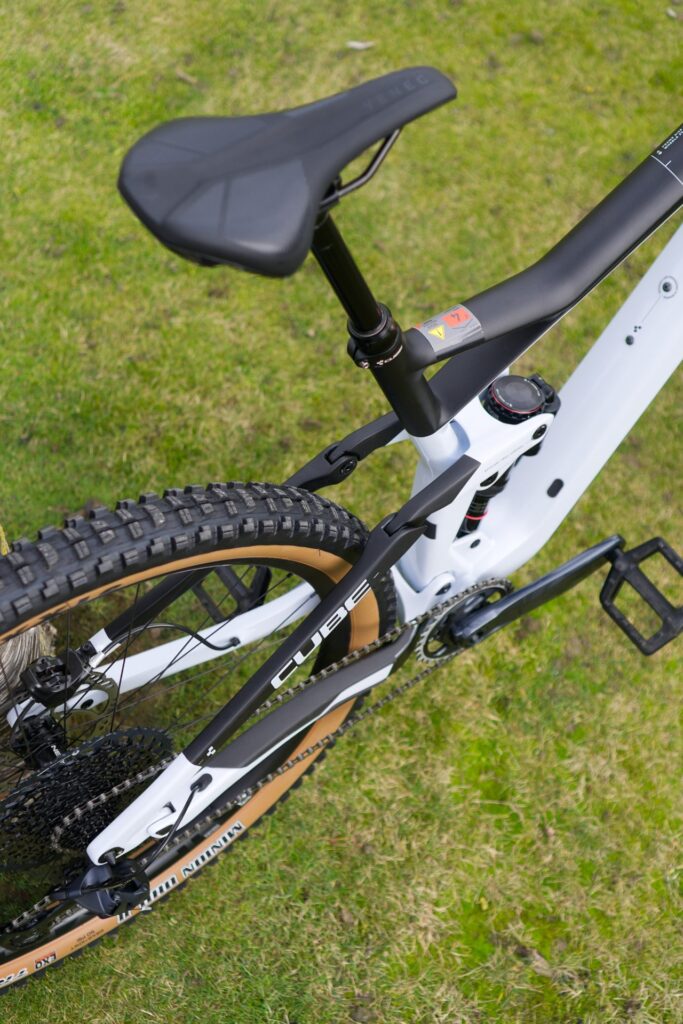 Cube Stereo 150 C:62 Race 2022 Hinterbau, robuste Federung und Reifenprofil auf grünem Rasen.