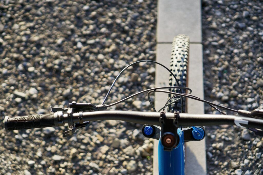 Cube Stereo 140 HPC 2022 Cockpit mit Lenker und Vorderreifen auf Kiesweg.