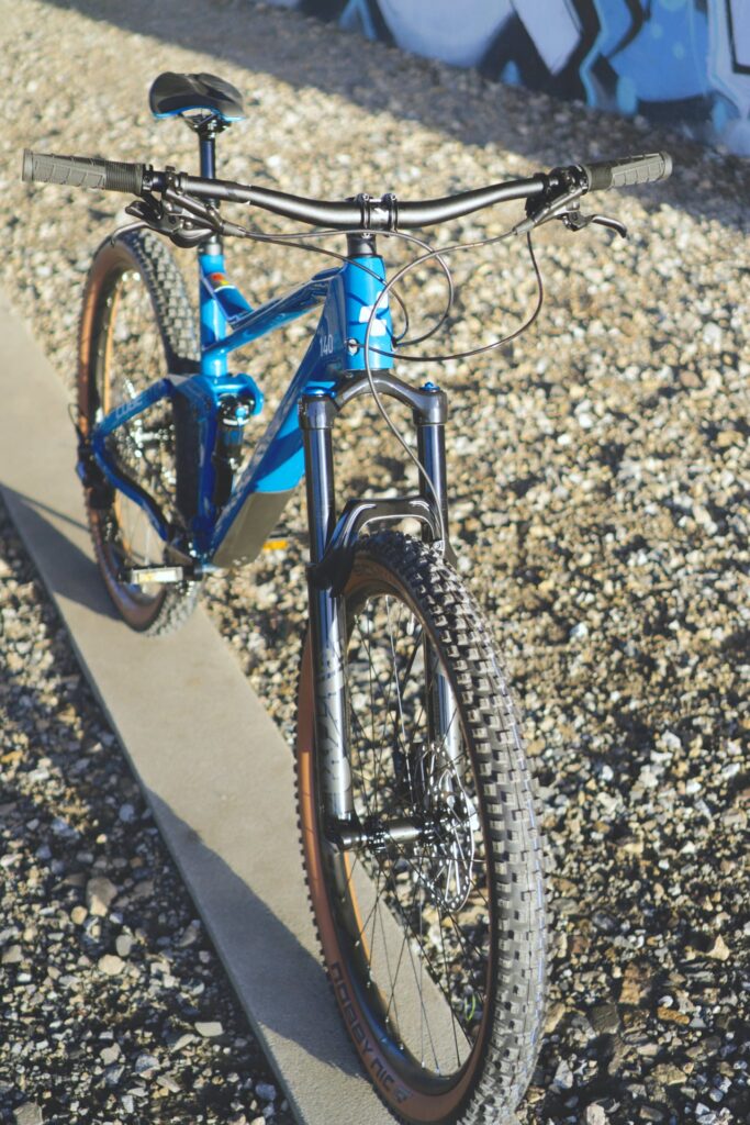 Blaues Cube Stereo 140 HPC Race 2022 Mountainbike auf Schotterweg, Fokus auf Vorderansicht und Federung.