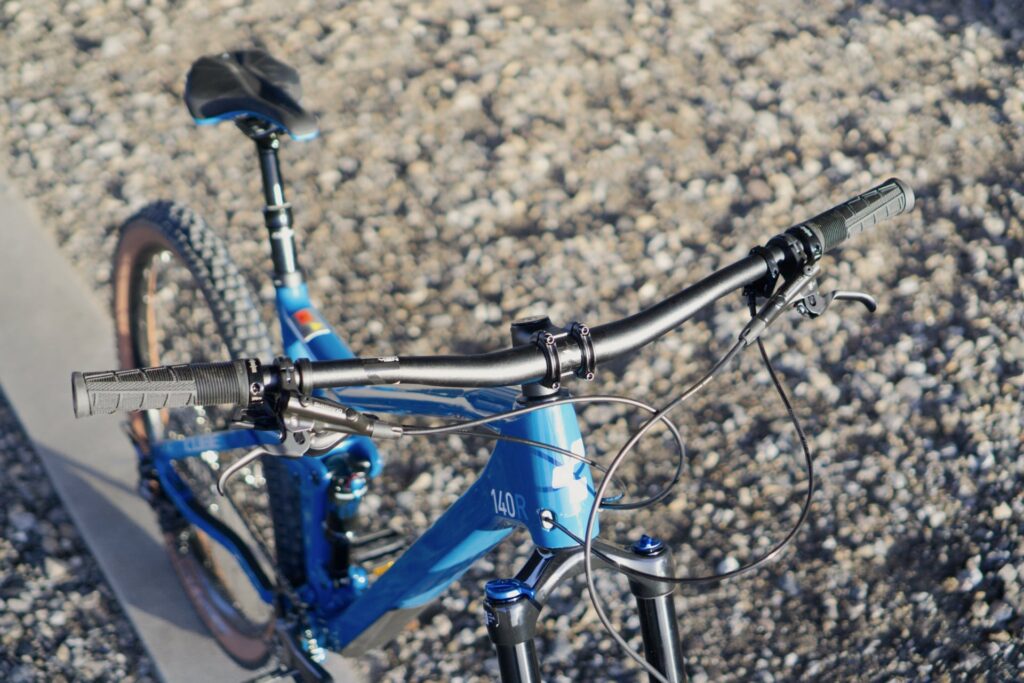 Cube Stereo 140 HPC Race 2022, Nahaufnahme des Lenkers und Rahmens auf Kiesweg.
