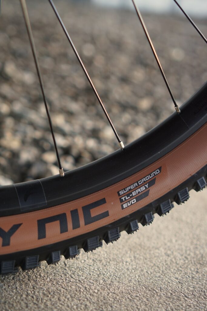 Nahaufnahme Cube Stereo 140 HPC Reifen mit Nobby Nic Profil auf Schotterweg, ideal für Offroad-Abenteuer.