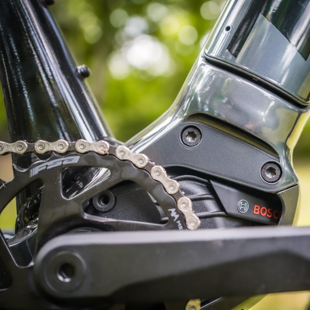 Trek Powerfly 4 2022 mit Bosch Performance CX-Motor, Detailansicht der Kette und Antriebseinheit im Grünen.