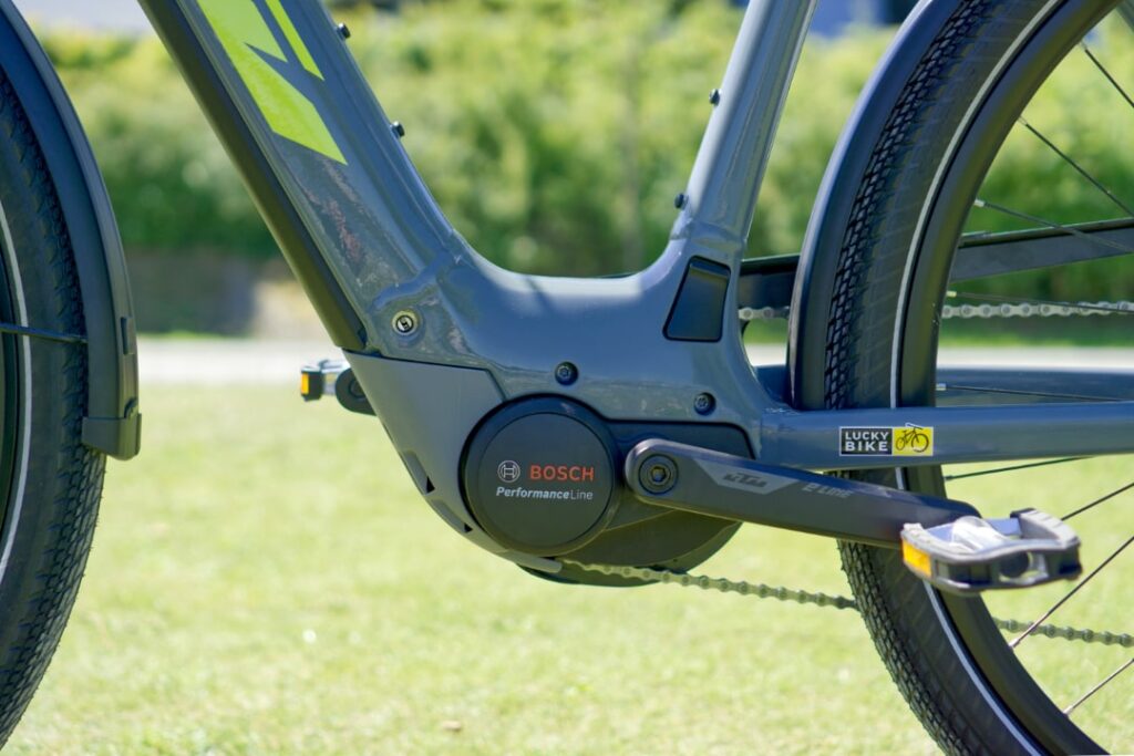 KTM Macina Sport Pro 2022 mit Bosch Performance Line Motor, Nahaufnahme des Antriebs auf grünem Hintergrund.