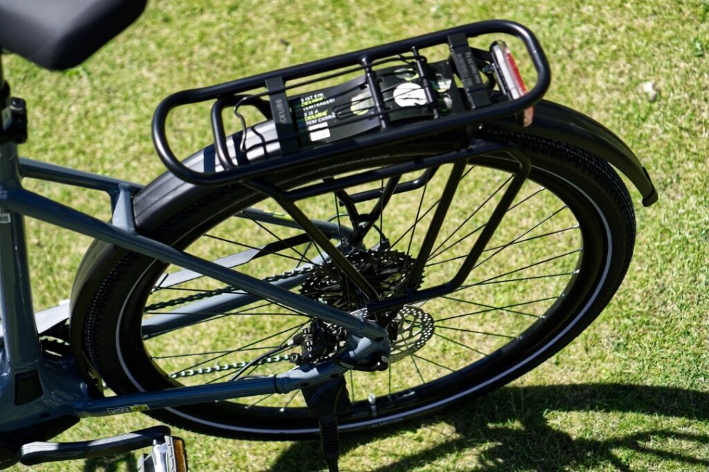 KTM Macina Sport Pro 2022 mit Racktime-Gepäckträger, Nahaufnahme des Hinterrads auf grünem Rasen.