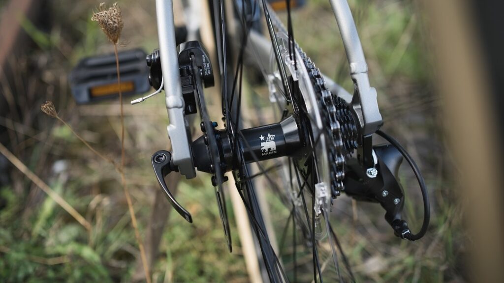 Detailansicht des Hinterrads eines Marin Lombard 1 Fahrrads mit Logo und Schaltwerk im Fokus.