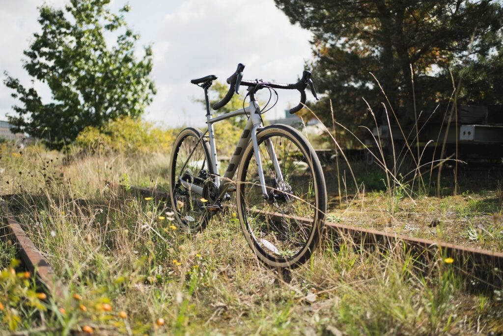 Marin Lombard 1 Fahrrad auf überwachsenen Bahngleisen bei sonnigem Wetter, umgeben von Bäumen und Wildblumen.
