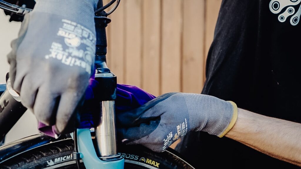 Federgabel eines Fahrrads wird im Frühjahr mit Handschuhen gereinigt.