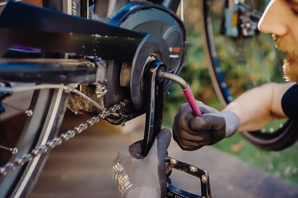 Fahrradmechaniker zieht Schrauben an der Kurbel fest, um das Rad für die Frühlingssaison vorzubereiten.