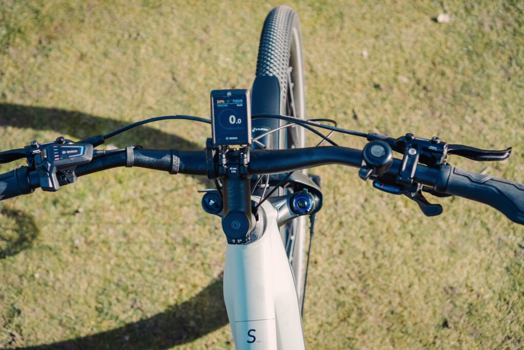 Cockpit des Cube Nuride Hybrid SLX 750 Allroad 2023 mit Bosch-Display und Bedienelementen auf grünem Hintergrund.