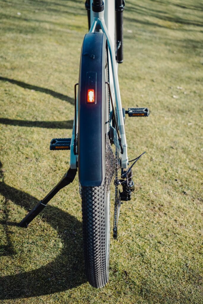 Cube Nuride Hybrid SLX 750 Allroad 2023, Rückansicht mit Schutzblech und Rücklicht auf grünem Rasen.