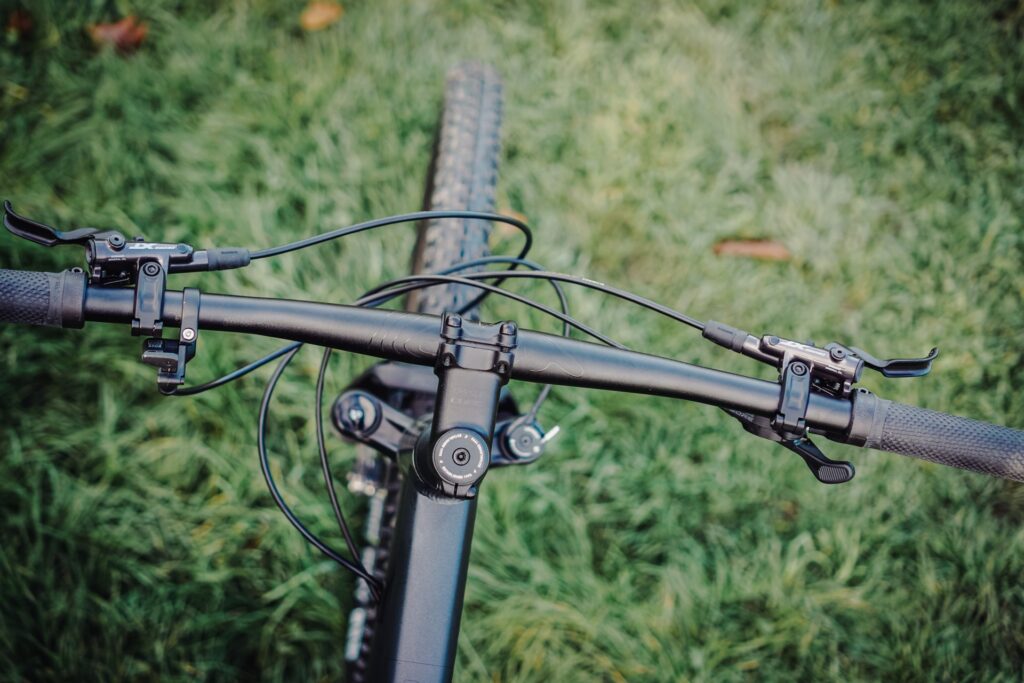Cube Reaction PRO 2023 Cockpit mit Lenker und Bremshebeln auf grünem Hintergrund.