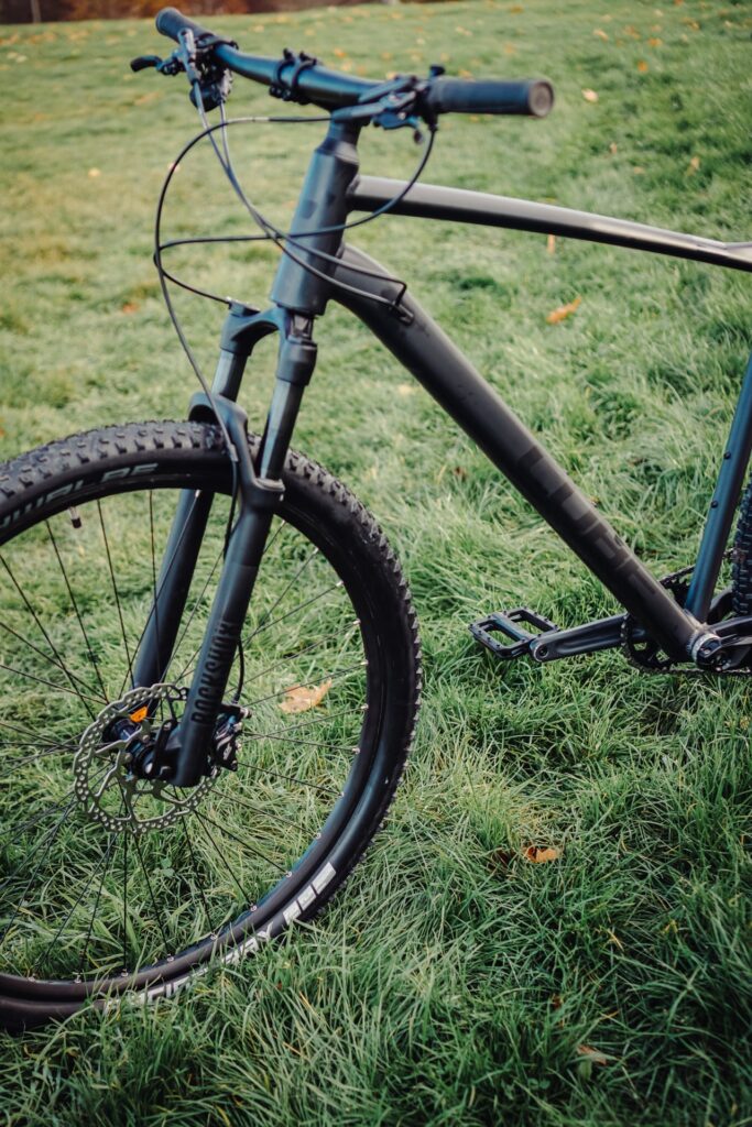 Cube Reaction PRO 2023 auf grünem Gras, zeigt Details des Rahmens und der Vorderradaufhängung.