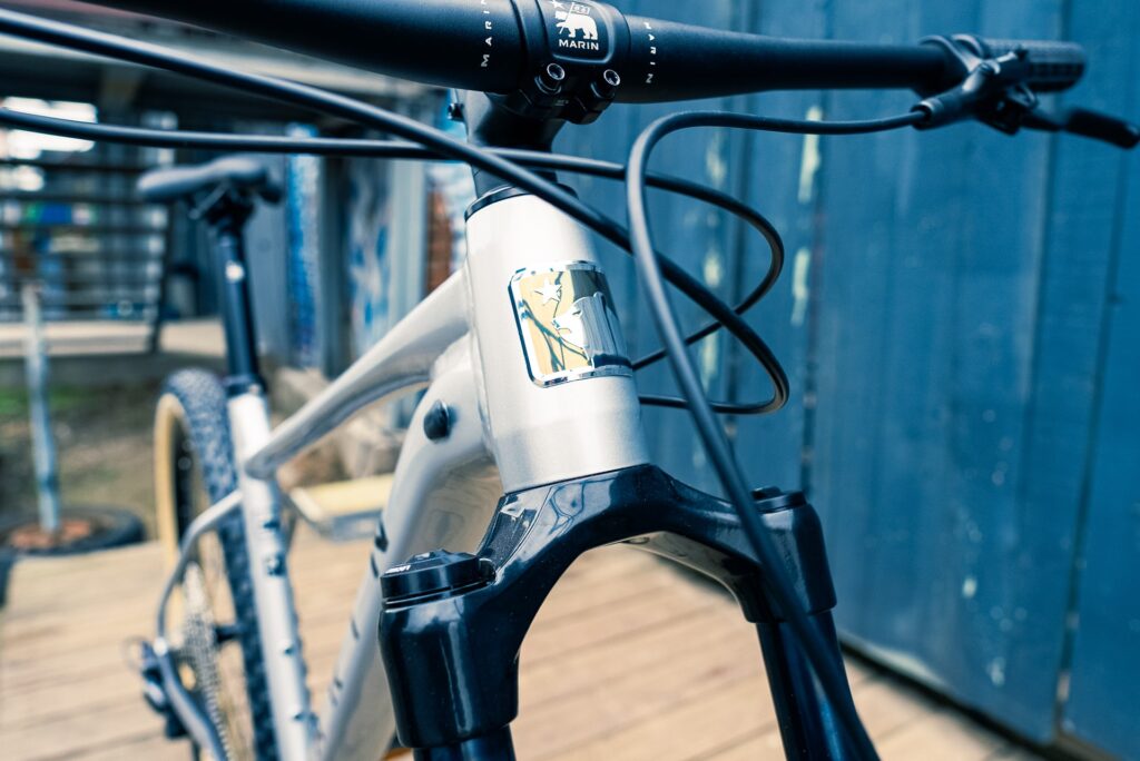 Nahaufnahme des Marin Team Marin 1 2023 Fahrrads mit Fokus auf Lenker und Rahmen im urbanen Hintergrund.