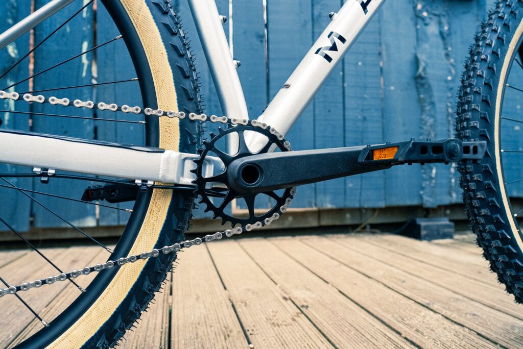 Mountainbike-Kurbel und Kette des Marin Team Marin 1, Detailansicht auf Holzterrasse.