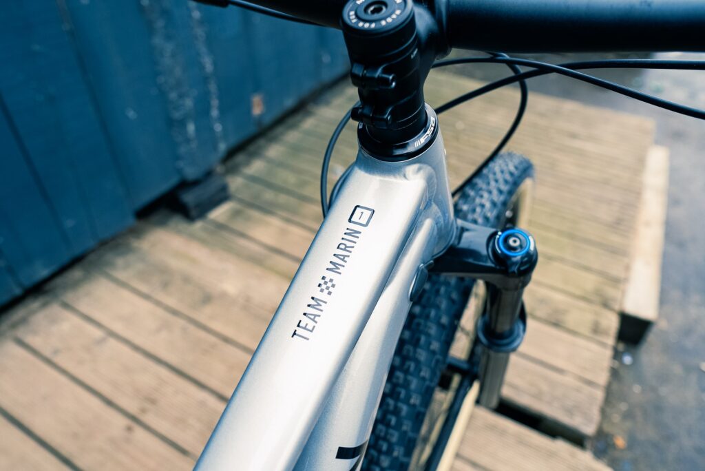 Nahaufnahme des Rahmens des Marin Team Marin 1 2023 mit Logo auf Holzuntergrund.