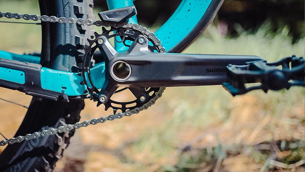 Shimano-Kurbel des Trek Roscoe 7 2023, Nahaufnahme der Fahrradkette und des Antriebs auf Waldweg.