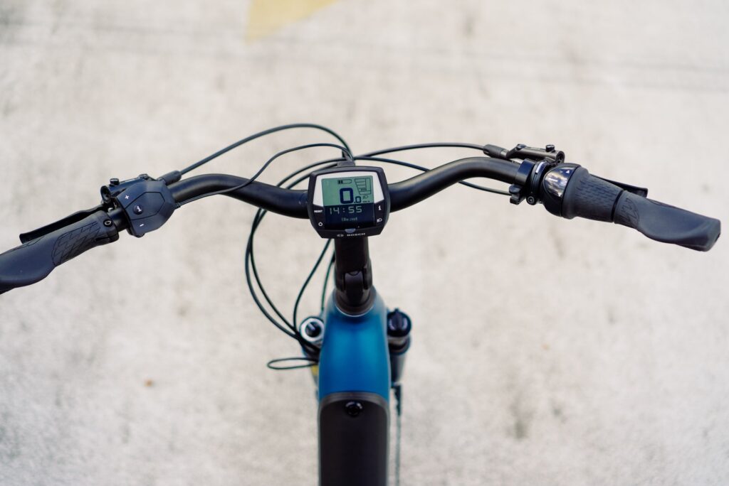 Cockpitansicht des Cube Supreme RT Hybrid EXC 2023 mit Display und Bedienelementen auf grauem Hintergrund.