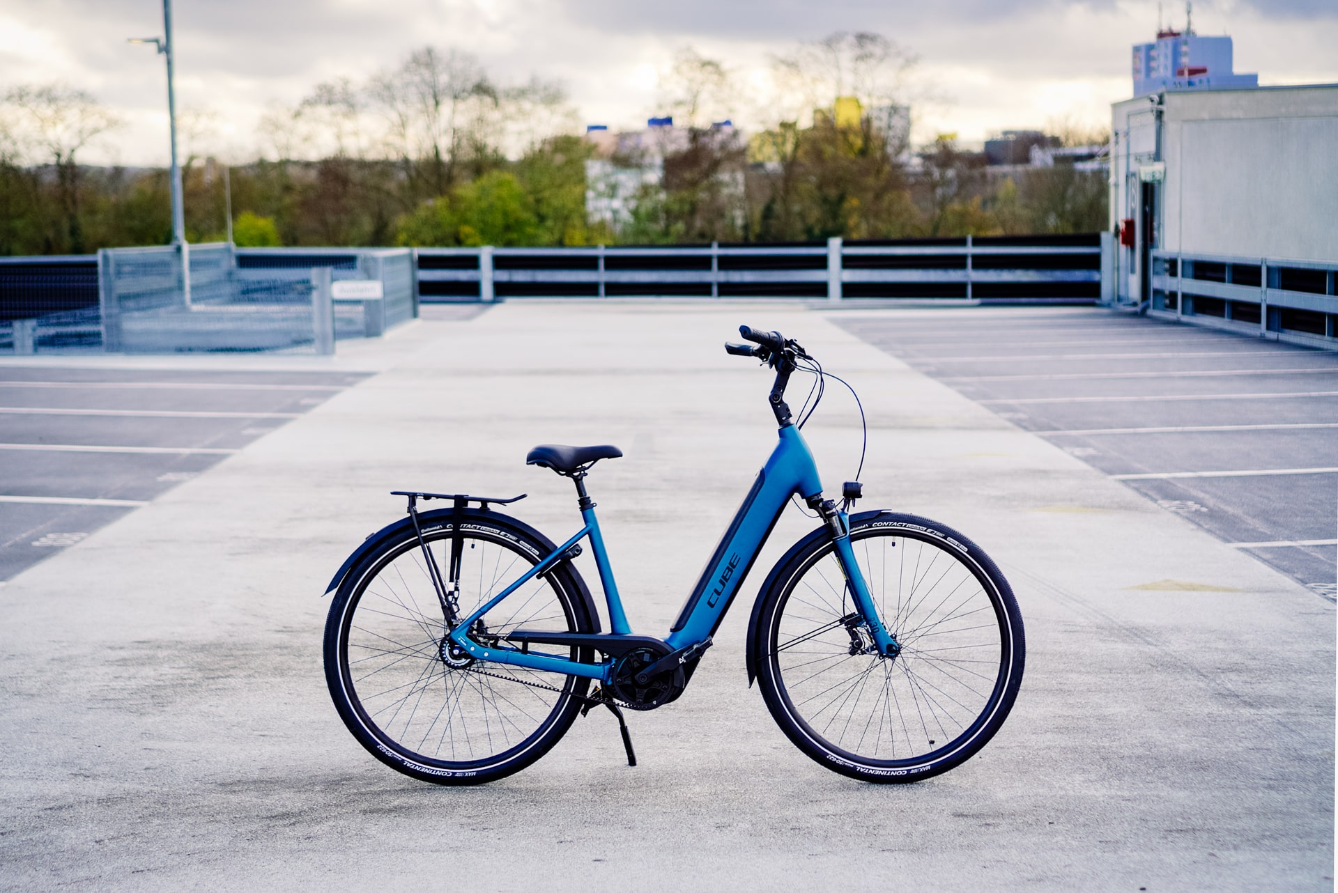 Cube Supreme RT Hybrid EXC 2023 E-Bike auf leerem Parkplatz, seitliche Ansicht, modernes Design.