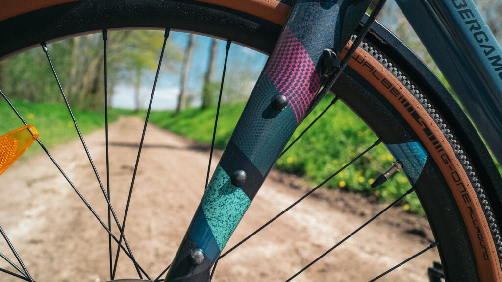 Detailansicht der Gabel des Bergamont Grandurance RD 5 2023 auf einem Feldweg, zeigt bunte Muster und Reifenprofil.