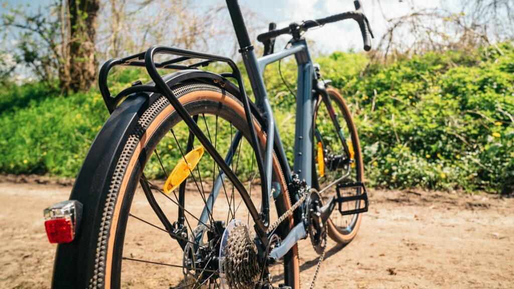 Heckansicht des Bergamont Grandurance RD 5 2023 auf einem Feldweg, Fokus auf Gepäckträger und Hinterrad.
