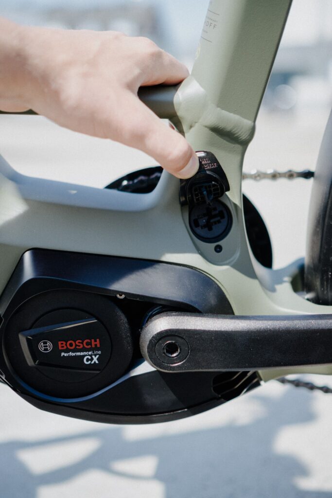 Bosch Performance Line CX Motor am Kalkhoff Entice E-Bike, Nahaufnahme der Ladebuchse mit Handinteraktion.