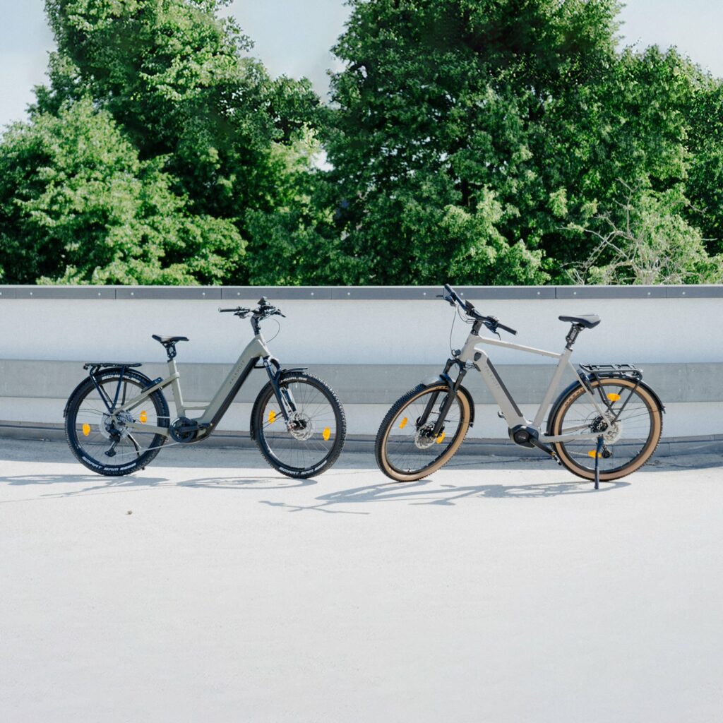 Zwei Kalkhoff Entice E-Bikes mit ABS vor grüner Kulisse im Test auf einem sonnigen Platz.