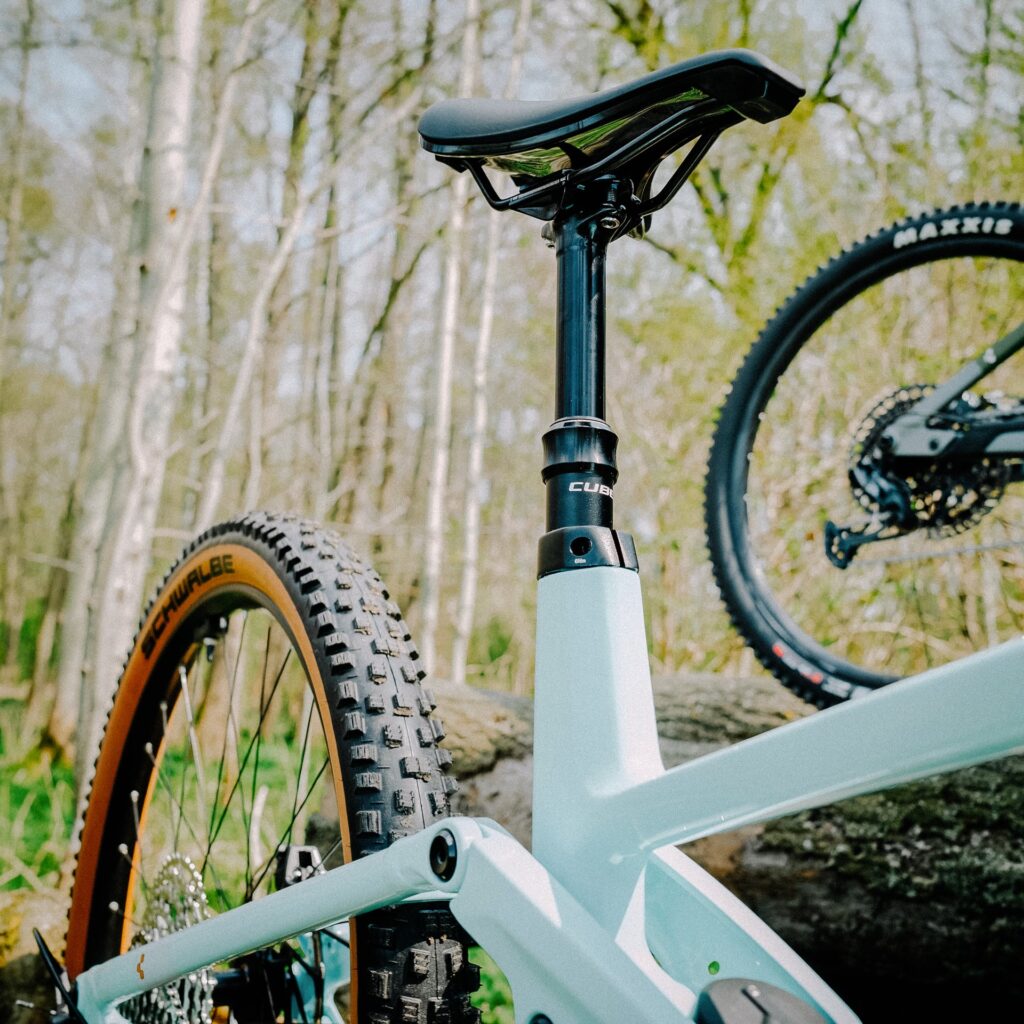 Cube Stereo Hybrid 140 HPC 2023 mit Variostütze im Wald, Detailansicht des Sattels und Hinterrads.