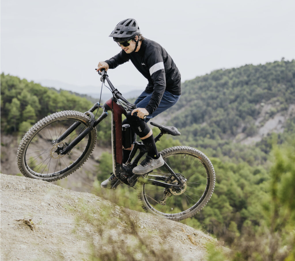 Mountainbiker auf steilem Hang mit Bosch E-Bike Performance Line SX, umgeben von grüner Landschaft.