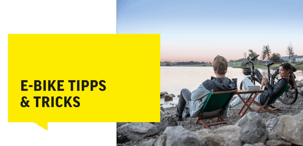 E-Bike-Tipps am See: Zwei Personen entspannen mit E-Bikes, genießen den Sonnenuntergang und tauschen Ratschläge aus.