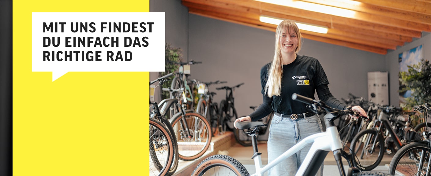 Frau lächelt im Fahrradgeschäft, umgeben von Fahrrädern. Text: „Mit uns findest du einfach das richtige Rad“.